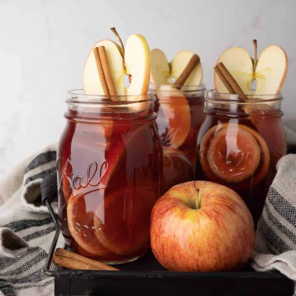 Mason Jars filled with apple shine Sangria and garnished with apple slices and cinnamon sticks